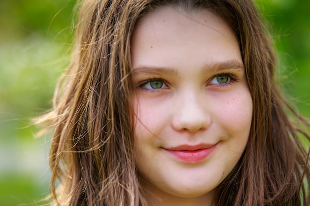 Retrato de una hermosa chica con cabello rubio oscuro en un parque de la ciudad en primavera