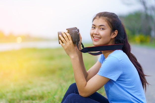 Retrato de la hermosa chica en camiseta azul y jeans sonriendo con una cámara en las manos