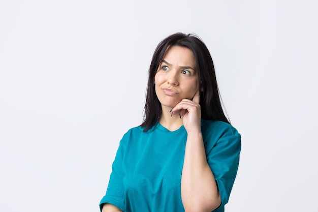 El retrato de una hermosa chica con una camiseta azul mira a un lado con una expresión pensativa y está considerando un plan de acción adicional