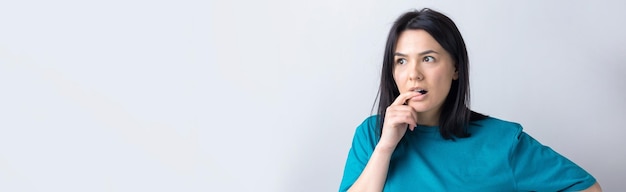 El retrato de una hermosa chica con una camiseta azul mira a un lado con una expresión pensativa y está considerando un plan de acción adicional