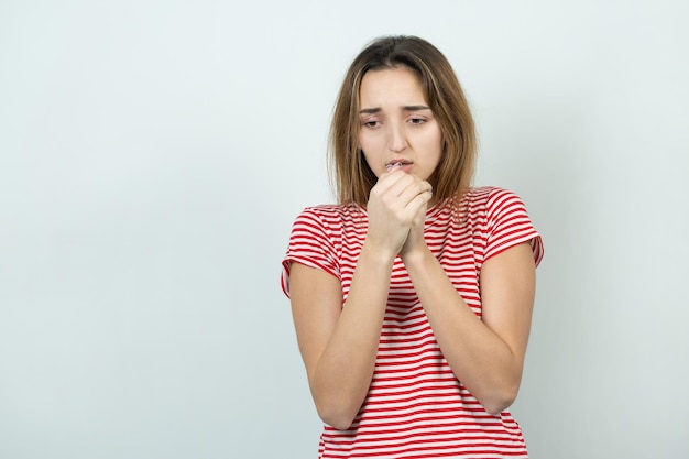 El retrato de una hermosa chica con una camiseta a rayas mira a un lado con una expresión pensativa y está considerando un plan de acción adicional