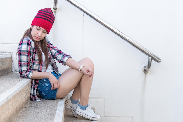 Retrato de hermosa chica hipster asiática en el fondo de la escalera Estilo de vida de mujer moderna Mujer feliz de Tailandia toma un concepto de foto