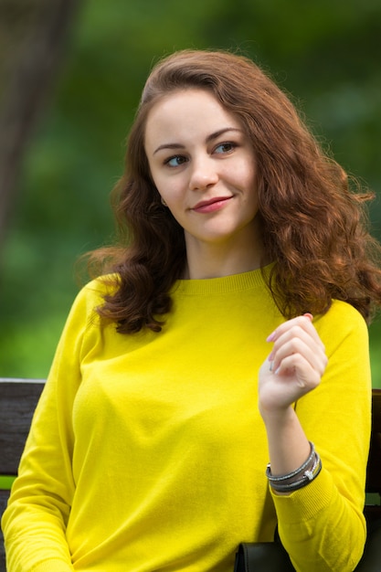 Retrato de la hermosa chica de moda en el banco en el parque