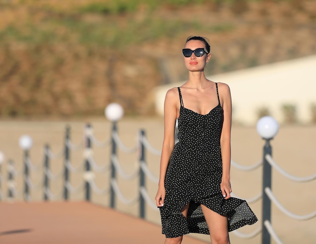 Foto retrato de una hermosa chica morena con gafas de sol con un vestido negro en verano