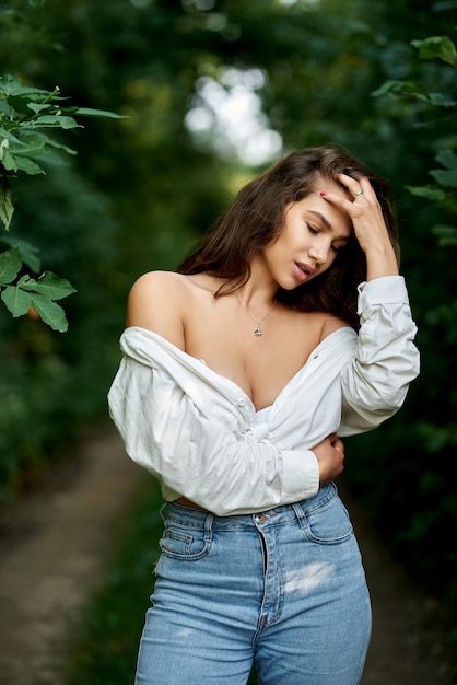 Retrato de una hermosa chica sexy con una camisa blanca desabrochada en el bosque El concepto de personas