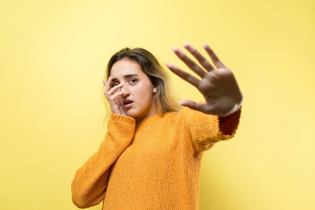 El retrato de una hermosa chica con un suéter naranja mira a un lado con una expresión pensativa y está considerando un plan de acción adicional