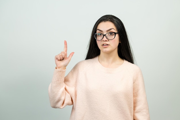 El retrato de una hermosa chica con un suéter rosa mira a un lado con una expresión pensativa y está considerando un plan de acción adicional