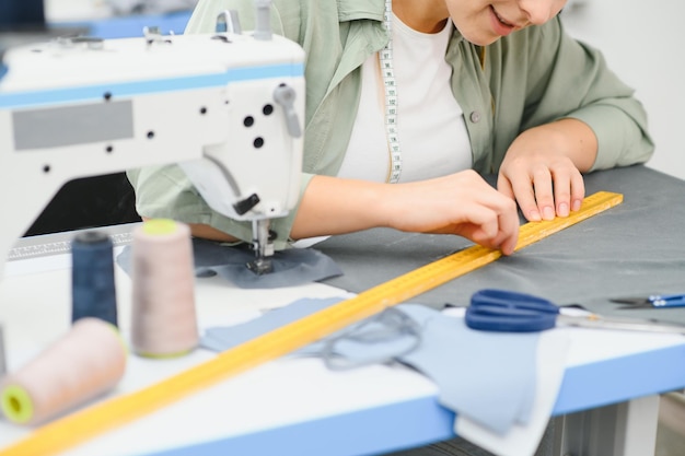 Retrato de una hermosa costurera que lleva una cinta métrica y trabaja en una fábrica textil