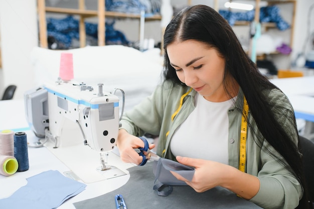 Retrato de una hermosa costurera que lleva una cinta métrica y trabaja en una fábrica textil