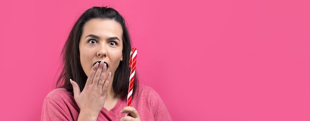 Retrato de hermosa dulce hermosa mujer alegre con cabello castaño lacio tratando de morder bastón de caramelo rojo navidad