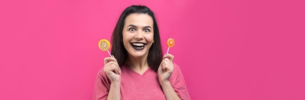 Retrato de una hermosa y dulce mujer alegre con cabello castaño lacio sosteniendo una piruleta cerca de los ojos