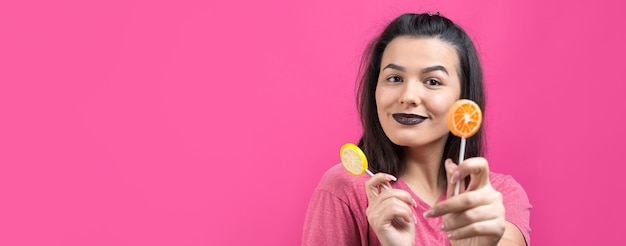 Retrato de una hermosa y dulce mujer alegre con cabello castaño lacio sosteniendo una piruleta cerca de los ojos