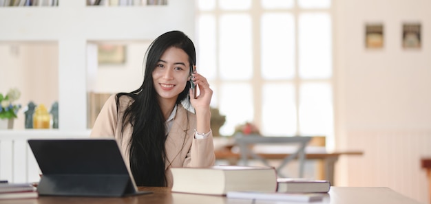 Retrato de hermosa empresaria trabajando en su proyecto en un lugar de trabajo cómodo y sonriendo a la cámara