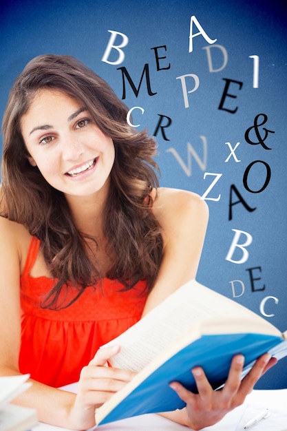 Foto retrato de una hermosa estudiante leyendo un libro azul sobre fondo azul.