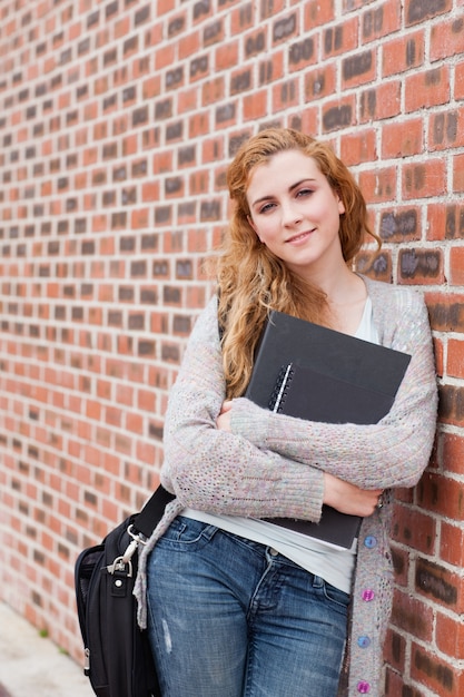 Retrato de una hermosa estudiante sosteniendo su carpeta