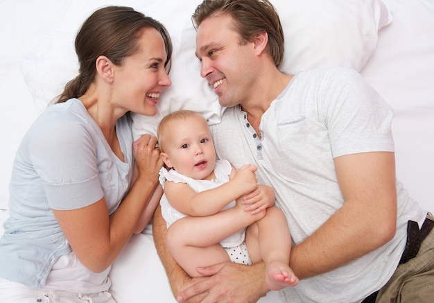 Retrato de una hermosa familia acostada en la cama con lindo bebé