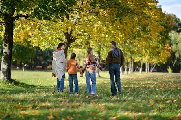 Retrato de una hermosa familia feliz en el parque otoño, vista posterior