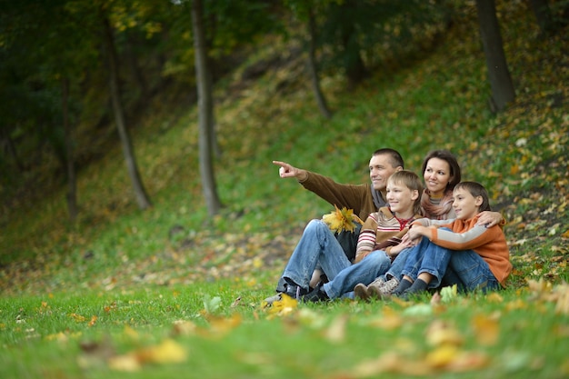 Foto retrato de una hermosa familia feliz sentada en el parque otoño