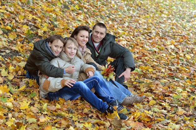 Retrato de una hermosa familia feliz sentada en el parque otoño