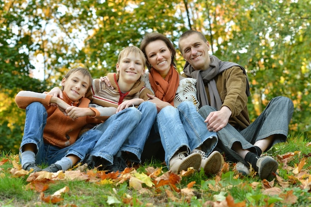 Retrato de una hermosa familia feliz sentada en el parque otoño