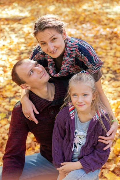 retrato de una hermosa familia en otoño entre las hojas caídas