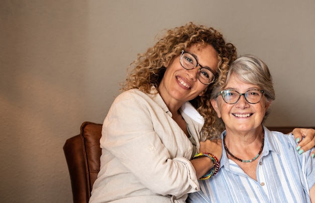 Retrato de hermosa hija adulta abrazando a su madre sonriendo, pasar tiempo juntos en casa