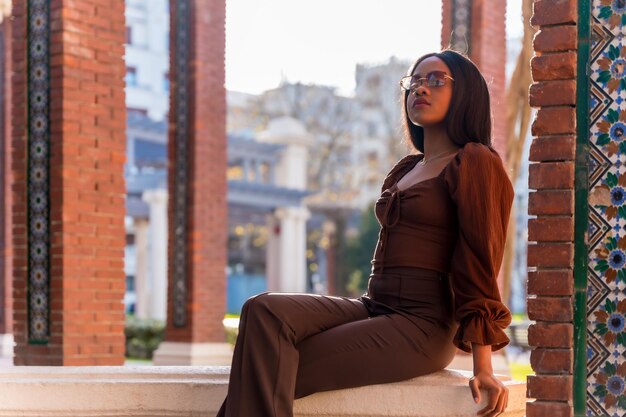 Retrato de una hermosa joven africana natural sonriendo sentada en un parque al sol