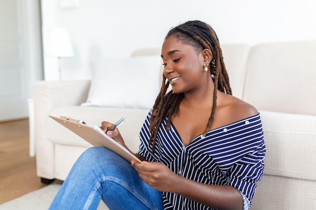 Retrato de hermosa joven africana trabajando en casa Mujer sentada y escribiendo notas