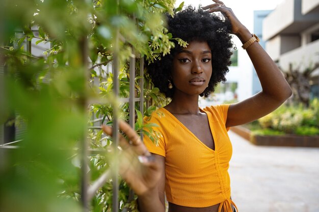 Retrato de una hermosa joven afroamericana posando contra el telón de fondo de un seto verde