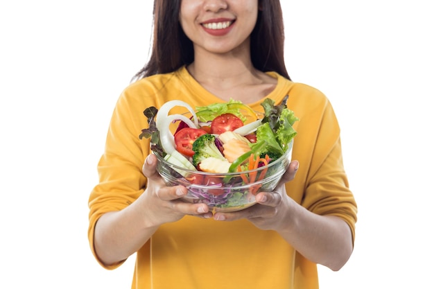 Retrato de una hermosa joven asiática comiendo ensalada de verduras aislada de fondo blanco.