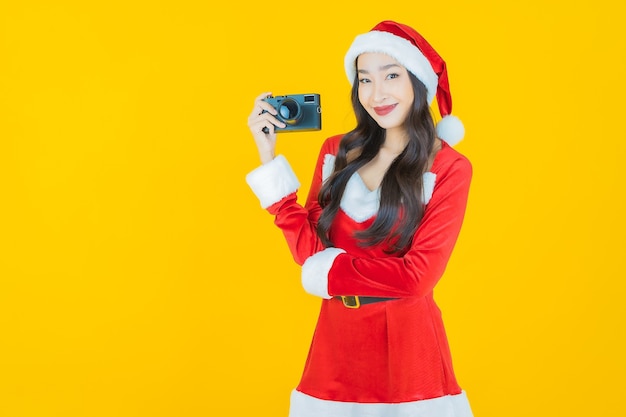 Retrato hermosa joven asiática llevar traje de Navidad con cámara en amarillo