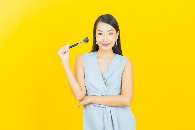 Retrato hermosa joven asiática con maquillaje cosmético cepillo