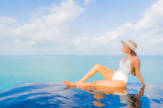 Retrato hermosa joven asiática relajarse sonrisa ocio alrededor de la piscina al aire libre en el hotel resort en viajes de vacaciones