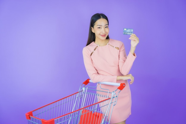 Retrato hermosa joven asiática sonrisa con cesta de la compra del supermercado sobre fondo de color