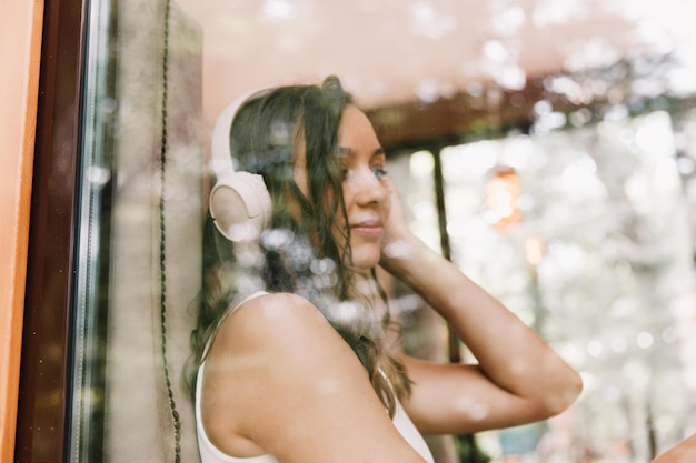 Retrato de una hermosa joven con auriculares que escucha música mientras está sentada en un café callejeroDisfruta de la generación musical Z