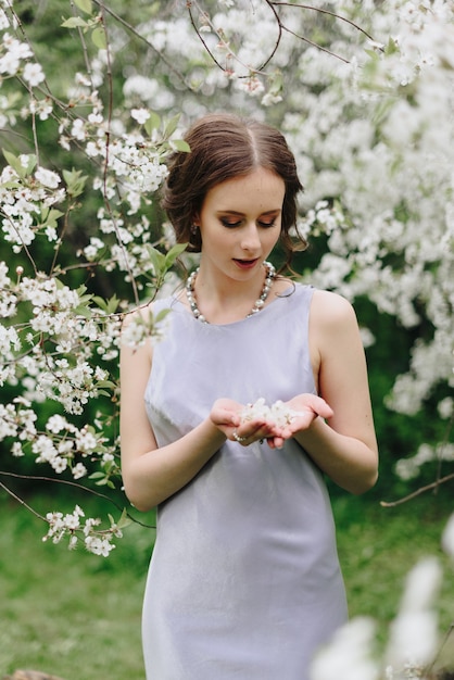 Retrato de una hermosa joven blanca delgada en una flor de cerezo de primavera 1