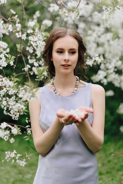 Retrato de una hermosa joven blanca delgada en una flor de cerezo de primavera 1