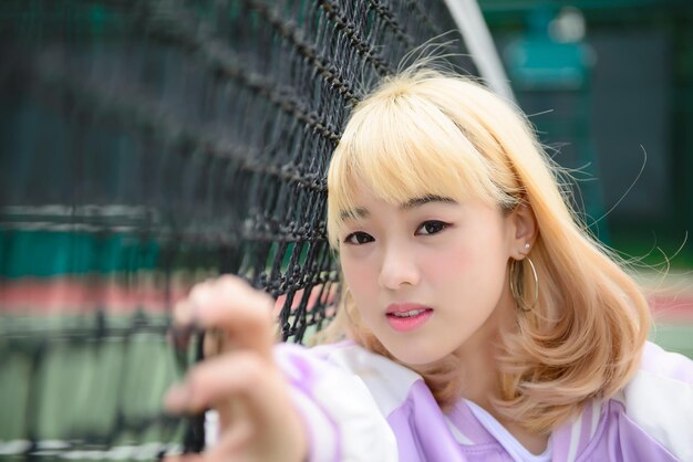 Retrato de una hermosa joven con cabello dorado en la cerca. Una mujer bonita sonriendo para tomar una foto al aire libre al estilo kawaii.