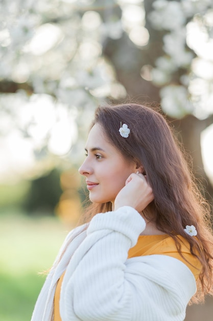 Retrato de una hermosa joven de cabello oscuro cerca de un árbol en flor Modelo feliz en el jardín Primavera