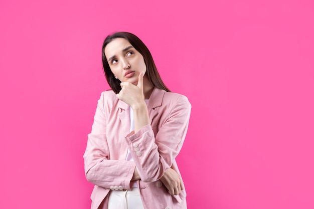 Retrato de una hermosa joven con chaqueta rosa pensando aislada en un fondo rojo