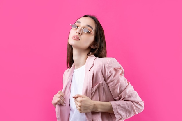 Retrato de una hermosa joven con chaqueta rosa pensando aislada en un fondo rojo