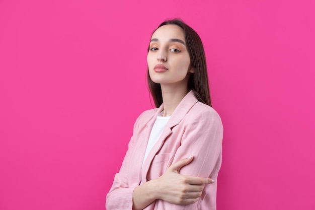 Retrato de una hermosa joven con chaqueta rosa pensando aislada en un fondo rojo