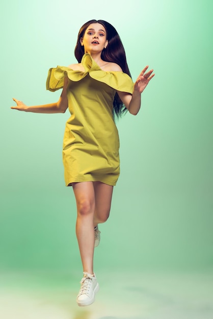 Retrato de una hermosa joven con un elegante vestido de verano posando aislada sobre un fondo verde