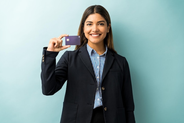 Retrato de una hermosa joven empresaria mostrando su tarjeta de crédito mientras se enfrenta a un fondo de color