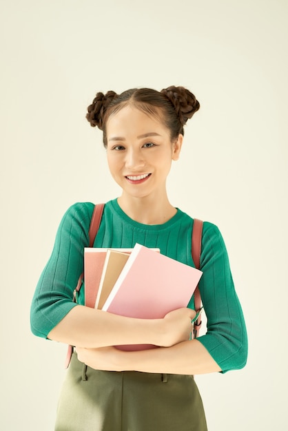 Retrato de una hermosa joven estudiante sosteniendo cuadernos.