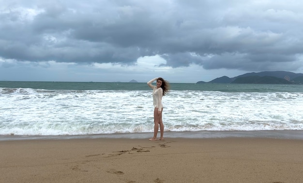 Retrato de una hermosa joven feliz positiva alegre alegre mujer disfrutando de vacaciones en el mar caminando en la playa de verano en un país tropical sonriendo divirtiéndose riendo en suéter de punto