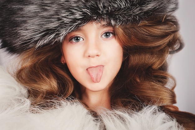 Retrato de una hermosa joven con gorra de piel saca la lengua