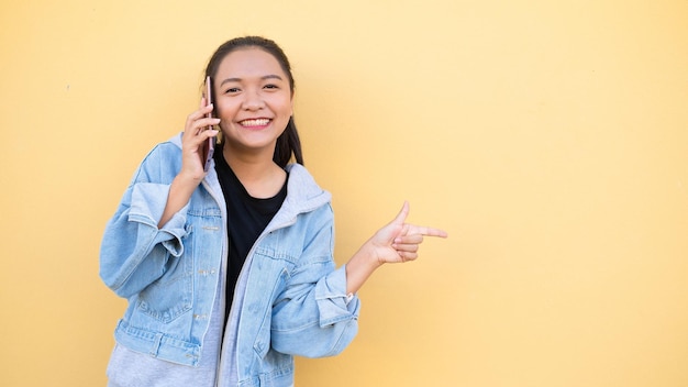 Retrato hermosa joven llevar chaqueta jean hablando con móvil en bcakground naranja, chica asiática.