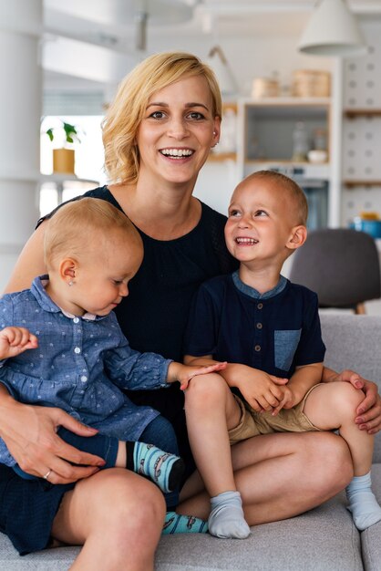 Retrato de hermosa joven madre sonriendo felizmente, abrazando a sus hijos. Familia, amor, concepto de niño.