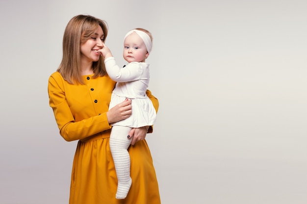 Retrato de una hermosa joven madre sonriente con un bebé en brazos